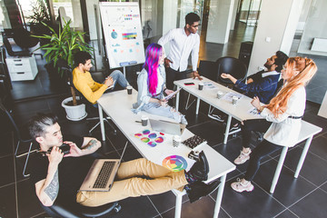 Group of multi ethnic executives discussing during a meeting. Business man and woman sitting around table at office and smiling. A team of young creative designers