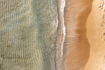 Sandy beach coastline with crystal sea water and small waves background.