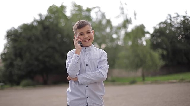 Handsome boy use phone outside. Little boy on the back yard of school