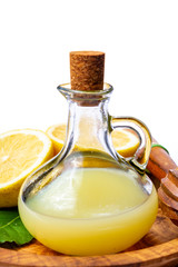 Fresh lemon juice made from ripe yellow Sicilian lemons used for cooking in glass bottle on olive wood plate