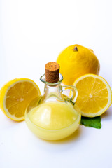 Fresh lemon juice made from ripe yellow Sicilian lemons used for cooking in glass bottle on olive wood plate