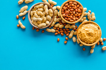 Make peanut butter with nuts and paste in bowl on blue background top view copyspace