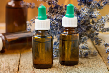 Bottles with aroma oil and bunch of dry lavender