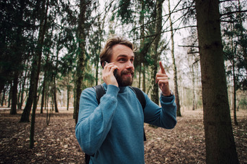 Young adult man talking on the phone standing over white brick wall stressed with hand on head, shocked with shame and surprise face, angry and frustrated.
