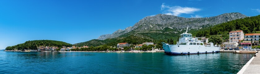 Fototapeta na wymiar Panorama Blick auf den Fährhafen in Drvenik auf Kroatien und die Berge im Hintergrund mit dem alten Dorf 