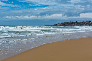 Scenic gray-blue clouds during sunrise over coastline with sandy beach and clear sea water in Agrigento, Sicily, Italy, summer vacation destination