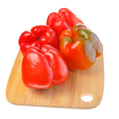 Four red peppers on cutting board