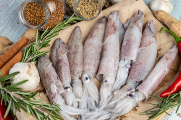 Fresh Raw Squids surrounded by spices and ingredient on a wooden table