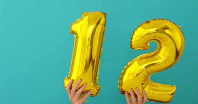 Gold foil number 12 twelve celebration balloon on a blue background