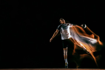 Caucasian young handball player in action and motion in mixed lights over black studio background. Fit male professional sportsman. Concept of sport, movement, energy, dynamic, healthy lifestyle.