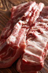 raw pork meat on wooden table. minimalism only meat brisket on bones or roast from which fry the beacon