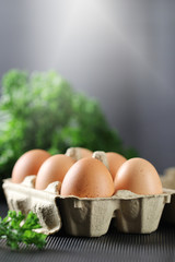 Fresh chicken eggs in carton box on black background.