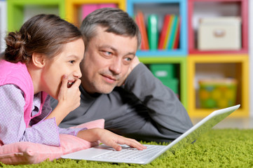 Portrait of father with little daughter using laptop