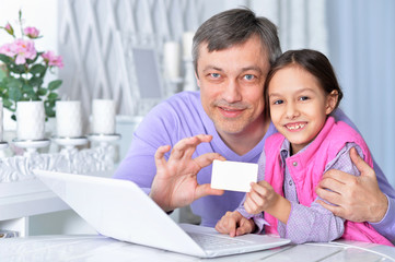 Father with little daughter using laptop shopping online