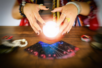 Psychic readings and clairvoyance concept - Crystal ball fortune teller hands and Tarot cards reading divination - obrazy, fototapety, plakaty