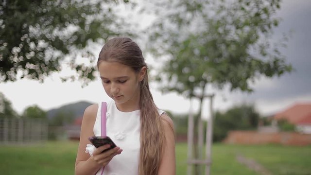 Young girl use phone during school break. Girl play online games