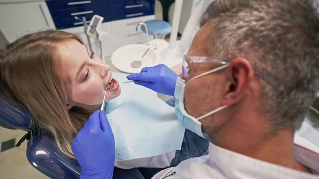 Side view of Pretty blond woman sitting in chair while having dental procedure with dentist at the dental clinic