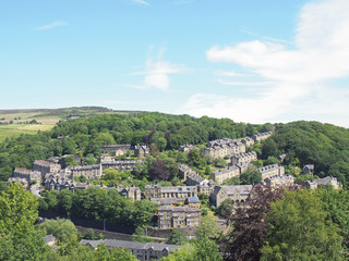 Fototapeta na wymiar a scenic aerial view of the town of hebden bridge in west yorkshire with streets of stone houses and roads between woodland trees and a blue summer sky