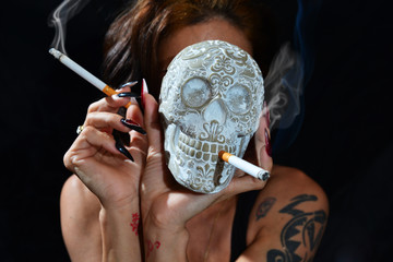 Frau mit Totenkopf der eine Zigarette raucht