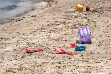 Fototapeta na wymiar A child's losted plastic sand buckets raker and scoop at the beach. Sunny day on Mediterranean sea