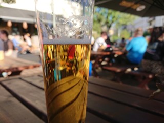 Glass with beer outdoors with people in the background.  Selective focus.