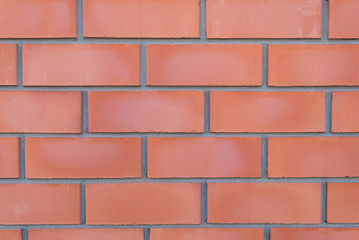 Fototapeta na wymiar Orange-red brick wall close-up with stitching. Wall texture in grunge style. Brick background for a subject shooting a flat lay. Concept of construction and interior design. Copy space