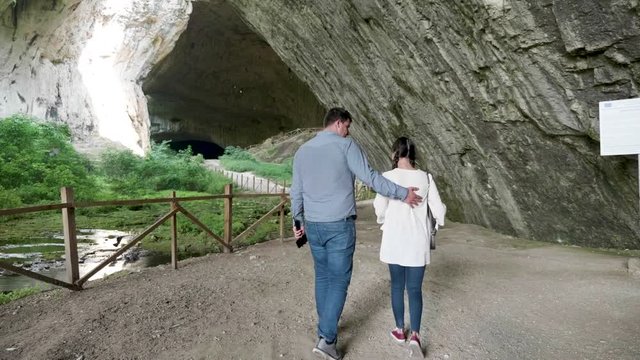 Couple walking into a big cave. Tourism and nature