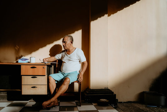 Asian Old Man Sitting On The Chair And Reading The Newspaper In The Morning