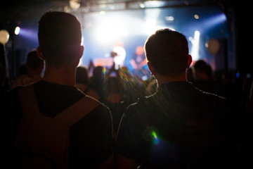 Cheering crowd in concert show having fun and applause in front of stage lights