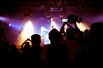 Cheering crowd in concert show having fun and applause in front of stage lights