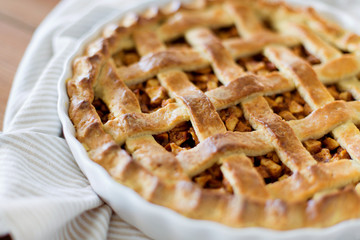 food, culinary and cooking concept - close up of apple pie in baking mold on kithchen towel