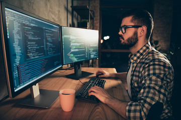 Close up side profile photo handsome he him his guy brainstorming briefing coder typing php css keyboard development outsource IT two monitors table office agency wear specs formalwear plaid shirt