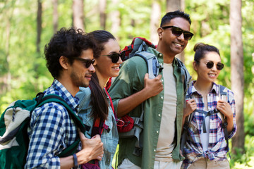 travel, tourism, hike and people concept - group of friends with backpacks in forest