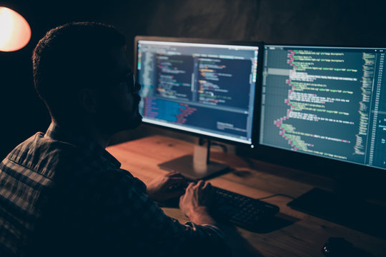 Close up back rear behind photo handsome he him his guy coder typing php css html keyboard development outsource IT processing language monitors table office wear specs formalwear plaid shirt