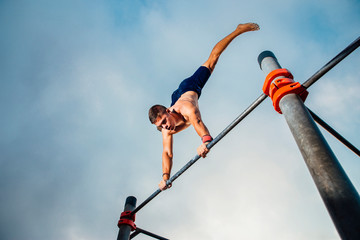 fitness, sport, training, calisthenics and lifestyle concept - young man exercising handstand on...