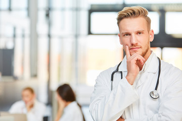 Junger Assistenzarzt in nachdenklicher Pose