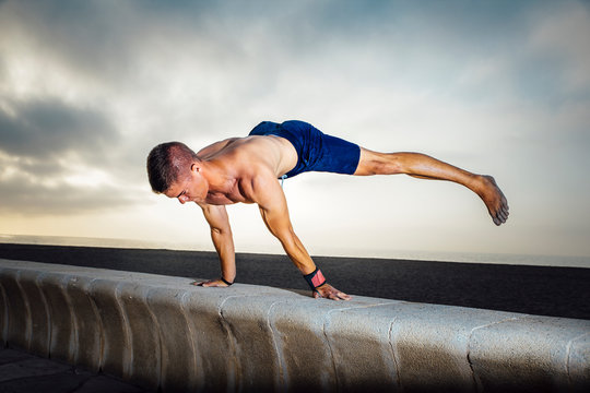 fitness, sport, training, calisthenics and lifestyle concept -  Young man training on the street doing straddle planche