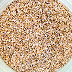 broken wheat groats in glass jar close-up