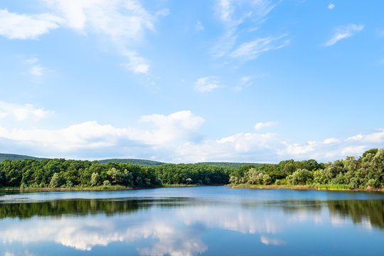 karst lake in green hills in calm summer evening