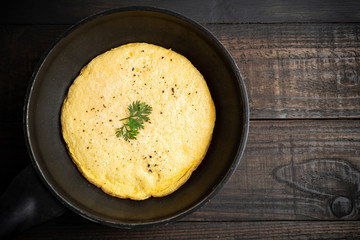 omelet in a pan on a wooden background.