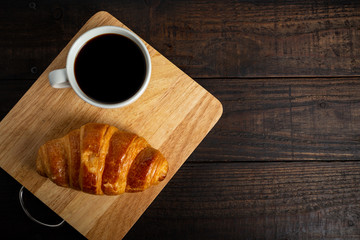 croissants and coffee on old wooden table.