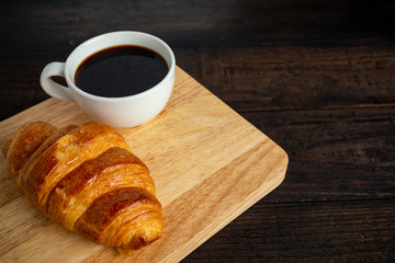 croissants and coffee on old wooden table.