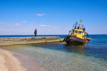 Fototapeta premium Fisherman and old ship on the Black Sea