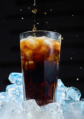 Glass of soda with ice on a dark background. Carbonated beverages. Close up.