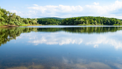 Fototapeta na wymiar panoramic view of lake in forest in calm evening