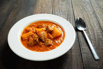 Goulash soup on wooden background.