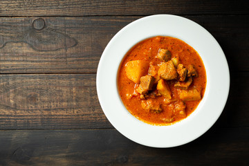 Goulash soup on wooden background.