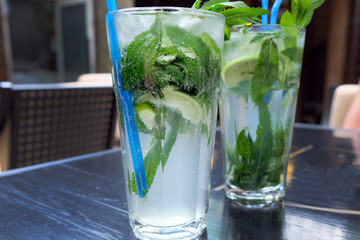 Mojito with mint and lime in a transparent glass with a straw. Delicious summer refreshing drinks, homemade soft drinks.