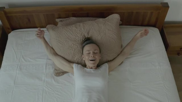 Happy caucasian woman between 30 and 35 years old in the bed in her room. Slow motion