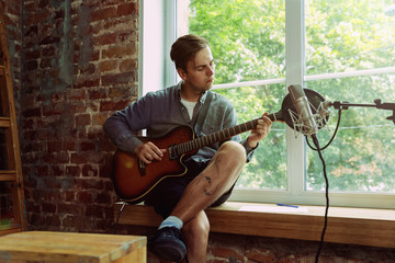 Young man recording music video blog, home lesson or song, playing guitar or making broadcast...